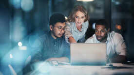 Cropped shot of three young businesspeople working together on a laptop in their office late at night.