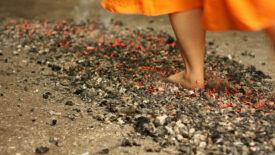 April 2024 Kenny Chapman Column feature image of a woman's legs with an orange dress walking over fire.