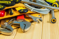 Necessary set of tools in the bag for plumbers on a wooden background.