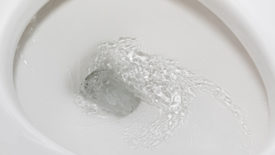 Motion blur of flushing water in toilet bowl. Plumbing, home repair and water conservation concept.