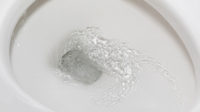 Motion blur of flushing water in toilet bowl. Plumbing, home repair and water conservation concept.