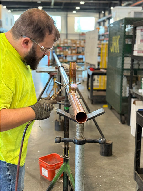 JH Kelly employee welding a pipe