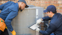 HVAC repairmen at work looking at a tablet.