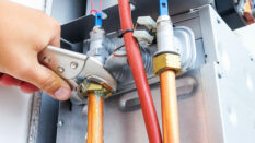 Close-up image of a plumber repairing a gas boiler of a heating home system in the boiler room.