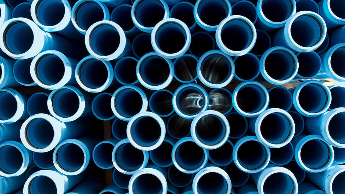 The ends of blue plastic water pipes that are stacked together in a pile.