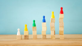 Colorful wooden figures placed on top of square wooden cube columns stacked from one to six.