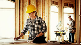 Woman architect looking over blueprints at home construction site.